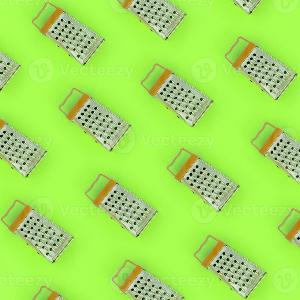 Small stainless steel graters lies on a pastel colored paper. Kitchen accessories. Tools for cooking. Flat lay top view photo