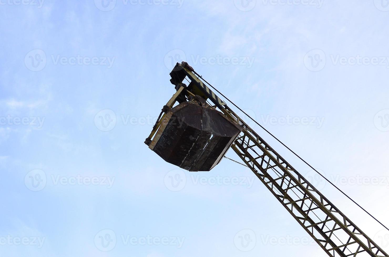 Old yellow mechanical clamshell grab on blue sky background photo