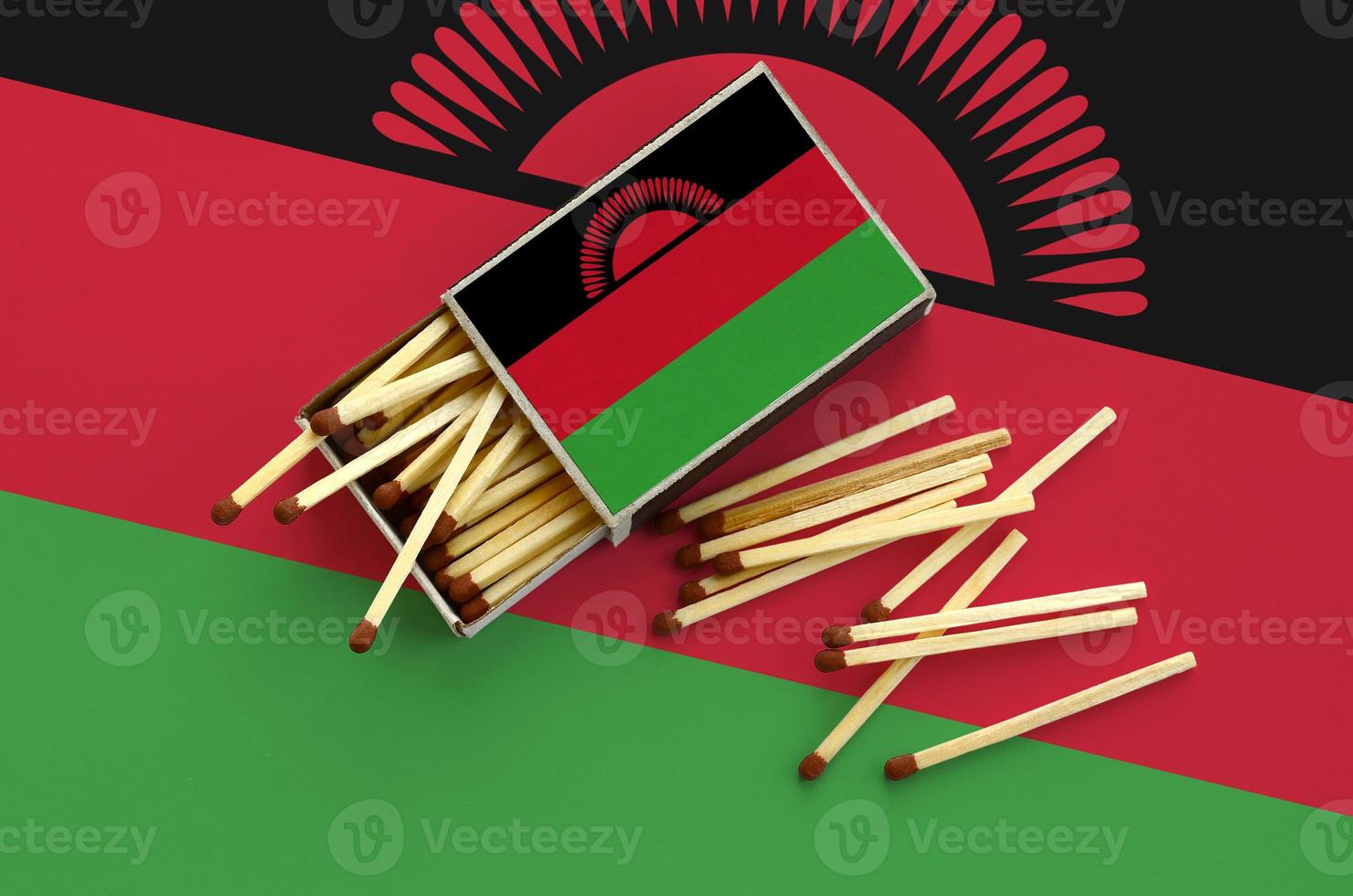Malawi flag  is shown on an open matchbox, from which several matches fall and lies on a large flag photo
