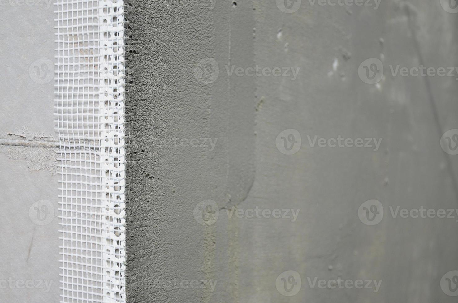 The texture of the wall, covered with gray polystyrene foam plates, which are coated with a reinforcing mixture with a plastic reinforcing profile corner. Stage of wall insulation photo