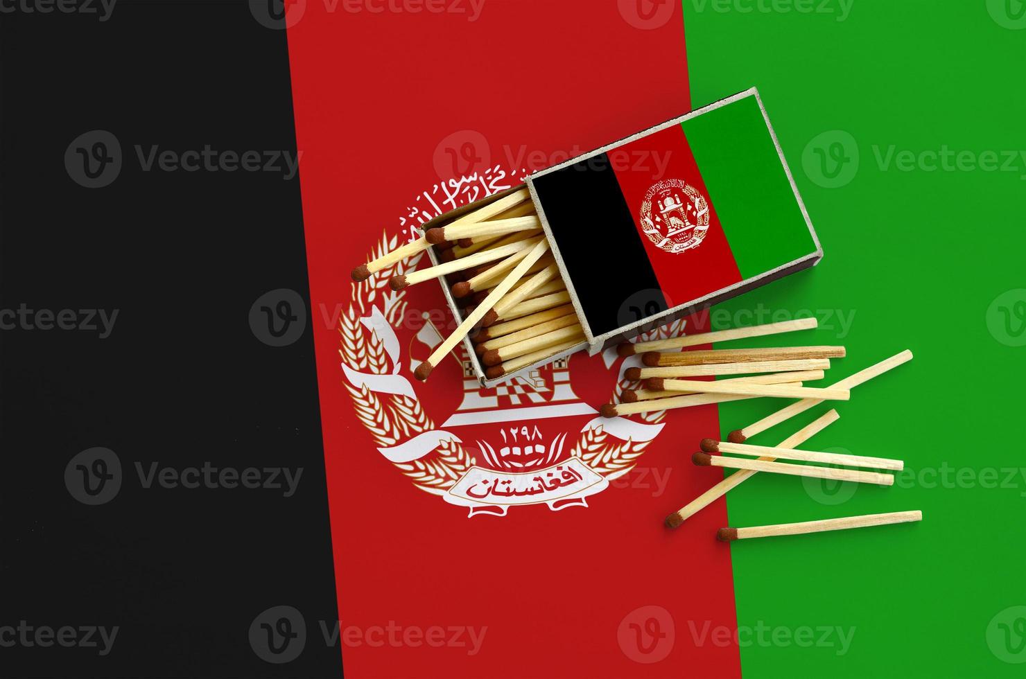 Afghanistan flag is shown on an open matchbox, from which several matches fall and lies on a large flag photo