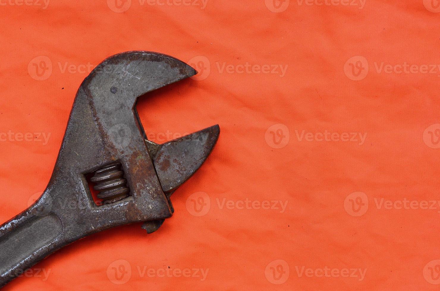 Adjustable wrench against the background of an orange signal worker shirt photo