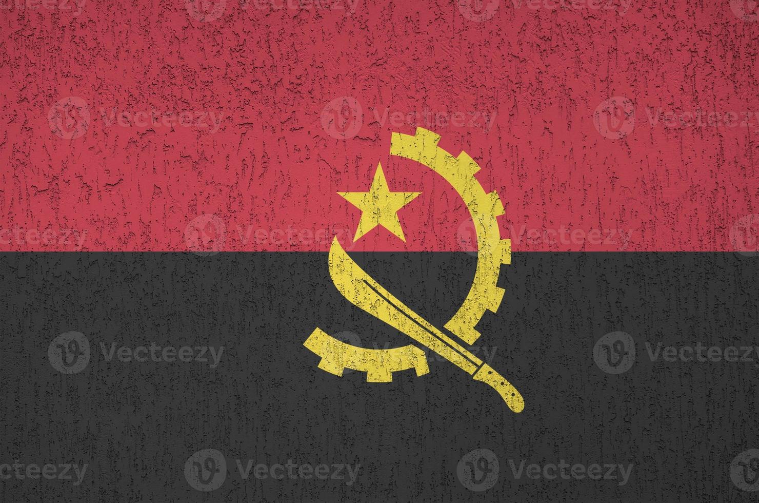 Angola flag depicted in bright paint colors on old relief plastering wall. Textured banner on rough background photo