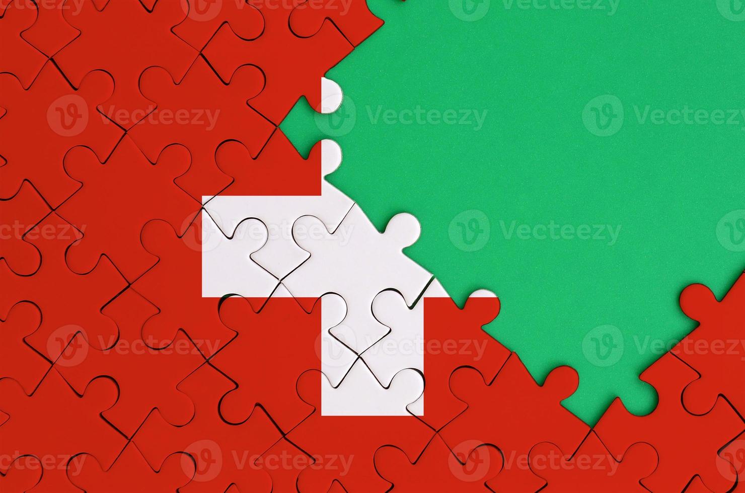 Switzerland flag  is depicted on a completed jigsaw puzzle with free green copy space on the right side photo