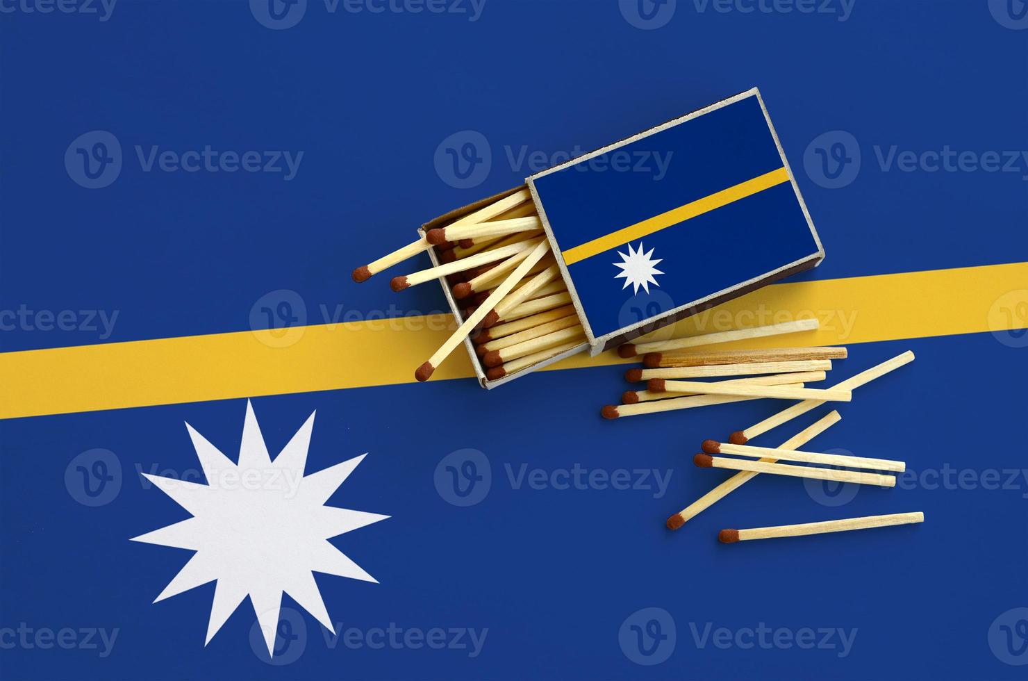 Nauru flag  is shown on an open matchbox, from which several matches fall and lies on a large flag photo