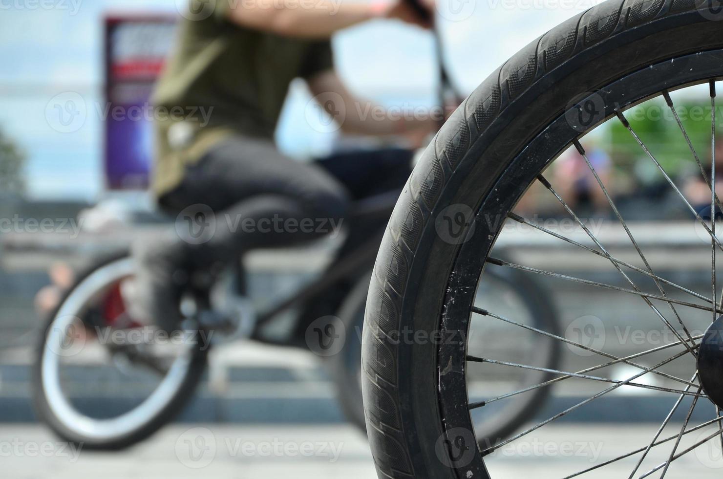 A BMX bike wheel against the backdrop of a blurred street with cycling riders. Extreme Sports Concept photo