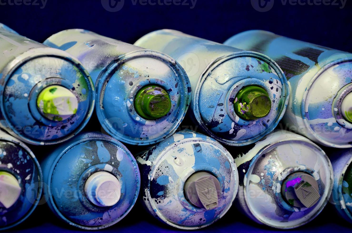 Still life with a large number of used colorful spray cans of aerosol paint lying on the treated wooden surface in the artist's graffiti workshop. Dirty and stained cans for spray art photo