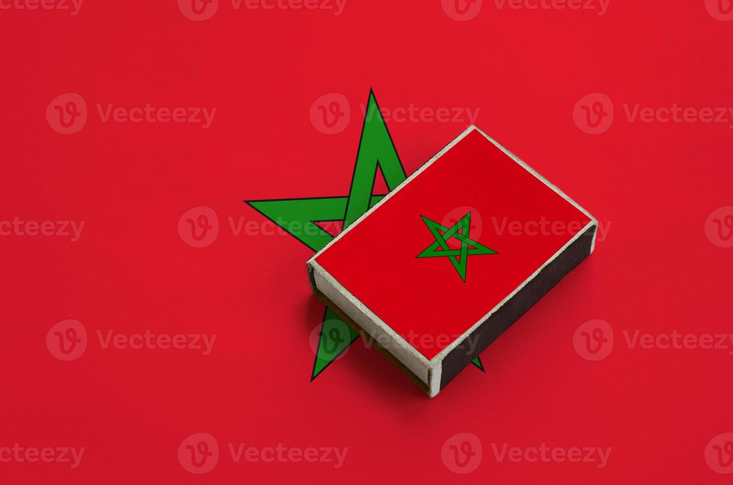 Morocco flag  is pictured on a matchbox that lies on a large flag photo