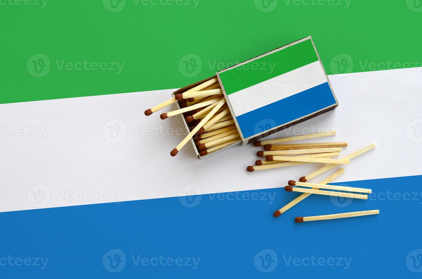 Sierra Leone flag  is shown on an open matchbox, from which several matches fall and lies on a large flag photo