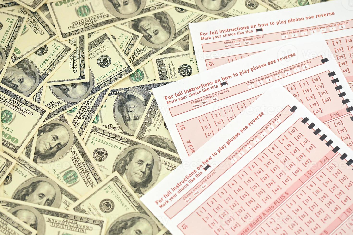 Pink gambling sheets with numbers for marking on big amount of hundred dollar bills. Lottery playing concept or gambling addiction. Close up photo