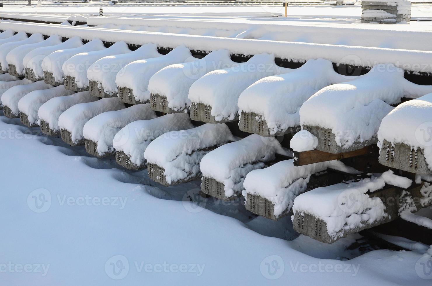 A lot of old rails and sleepers are stacked in a railway warehouse in winter. The concept of renewing a worn-out railway track photo
