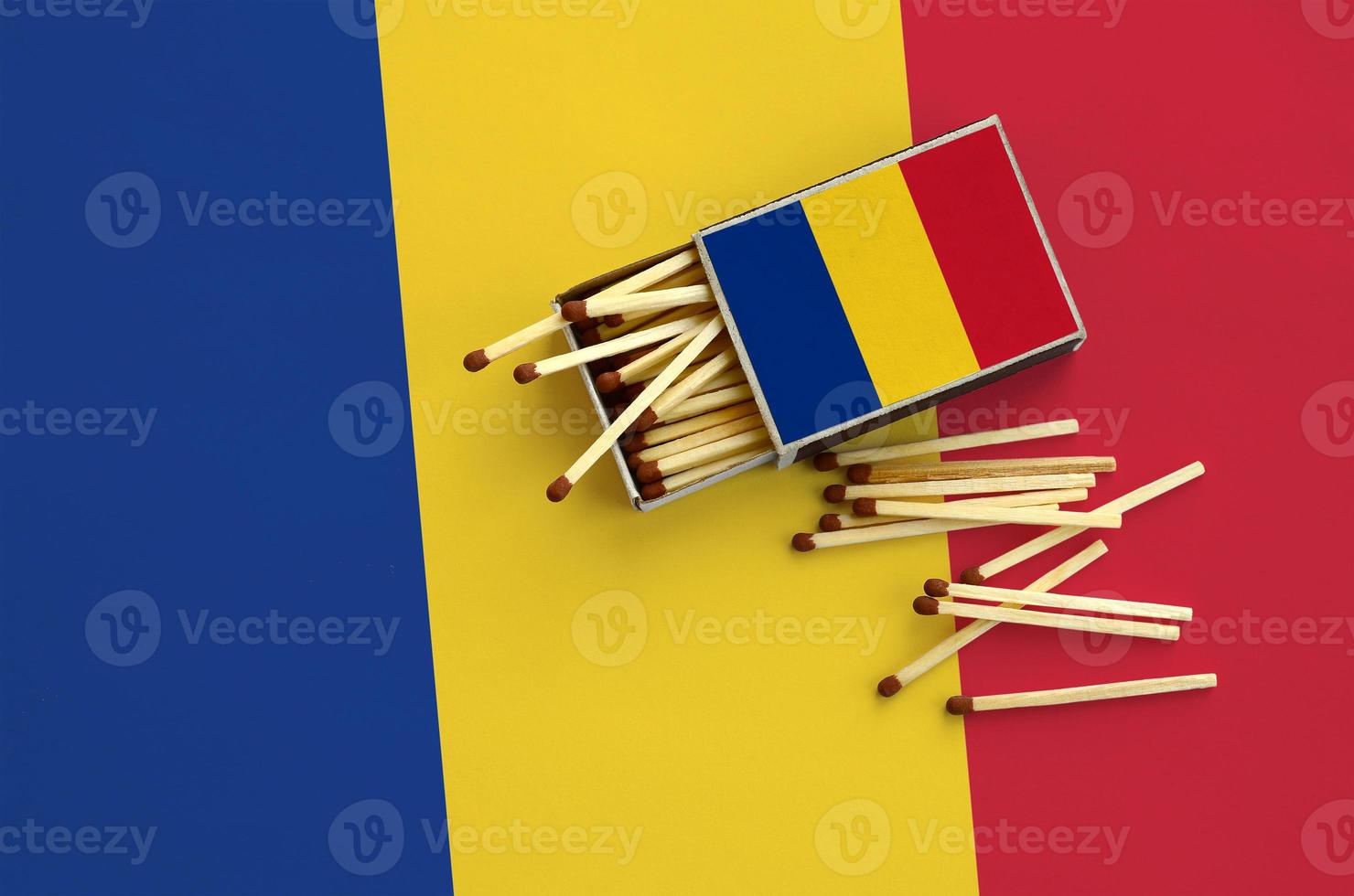 Romania flag  is shown on an open matchbox, from which several matches fall and lies on a large flag photo