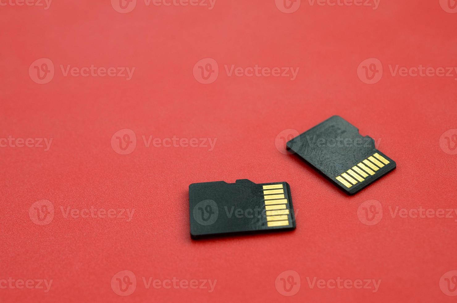 Two small micro SD memory cards lie on a red background. A small and compact data and information store photo