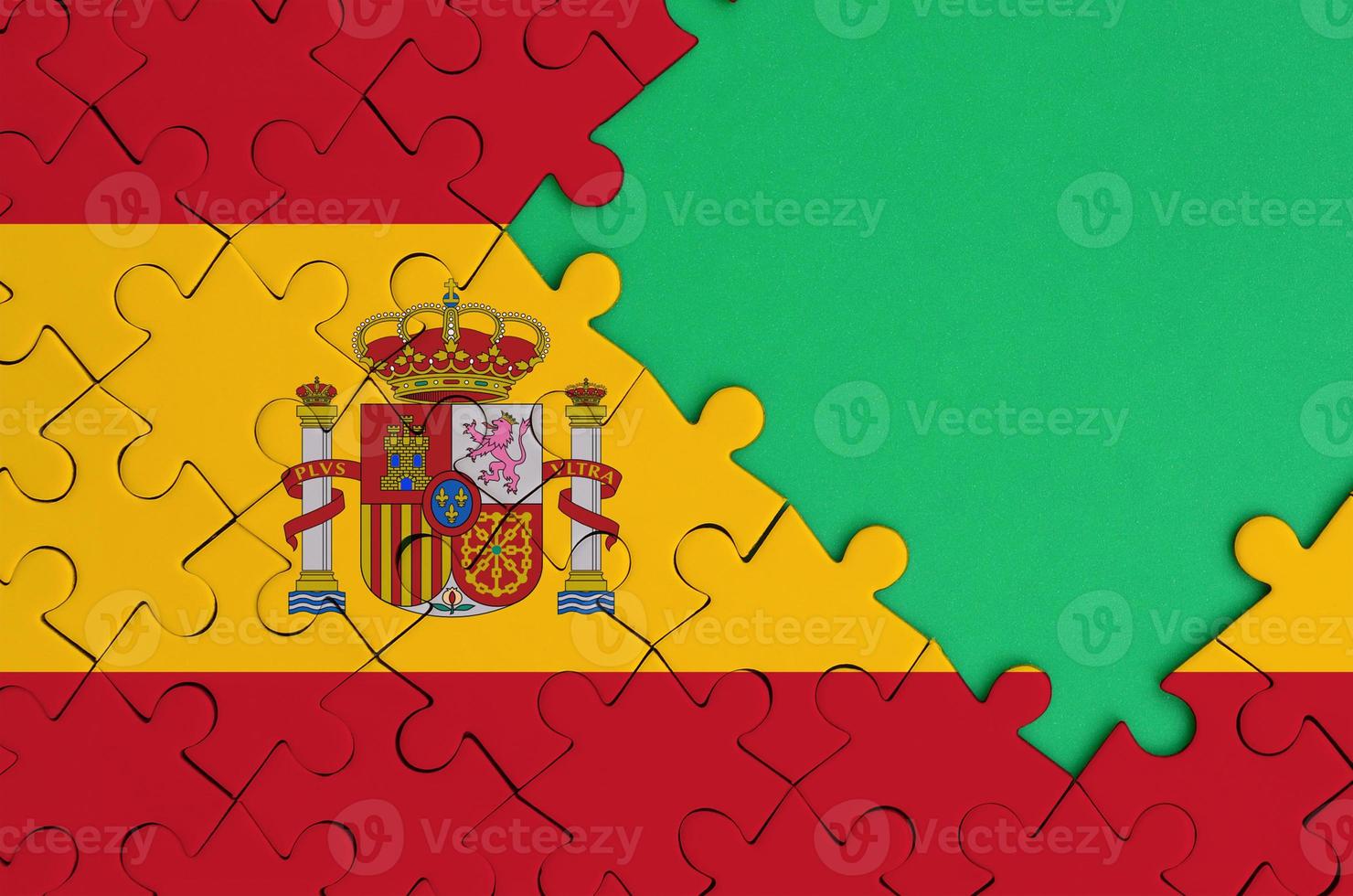 Spain flag  is depicted on a completed jigsaw puzzle with free green copy space on the right side photo