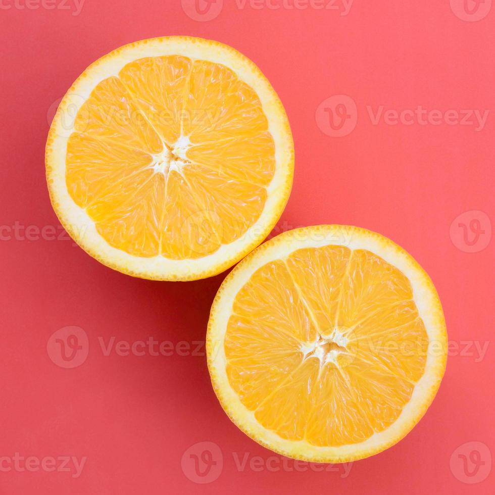 Top view of a several orange fruit slices on bright background in red color. A saturated citrus texture image photo