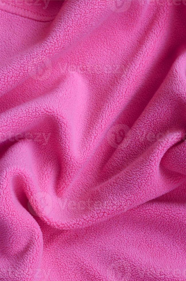The blanket of furry pink fleece fabric. A background of light pink soft plush fleece material with a lot of relief folds photo