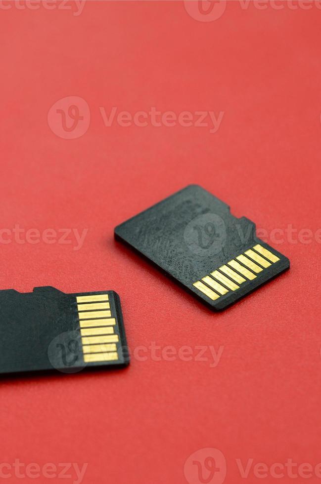 Two small micro SD memory cards lie on a red background. A small and compact data and information store photo