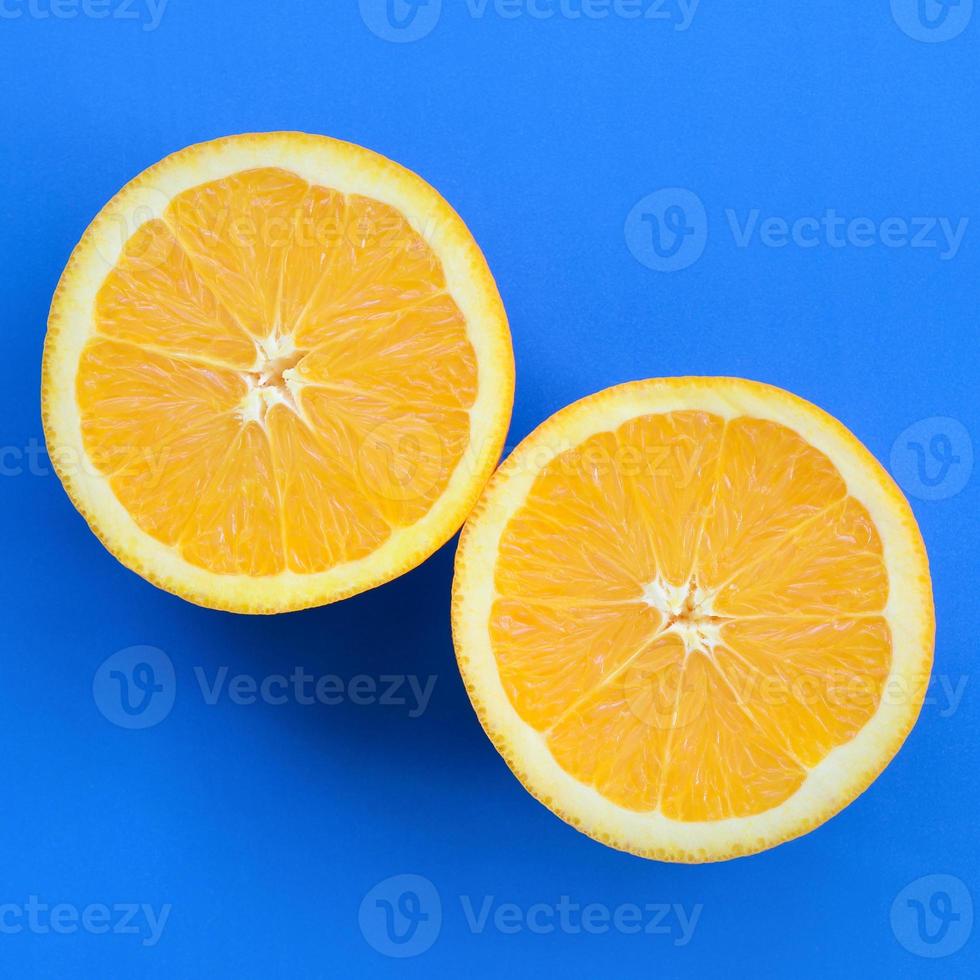 Top view of a several orange fruit slices on bright background in blue color. A saturated citrus texture image photo