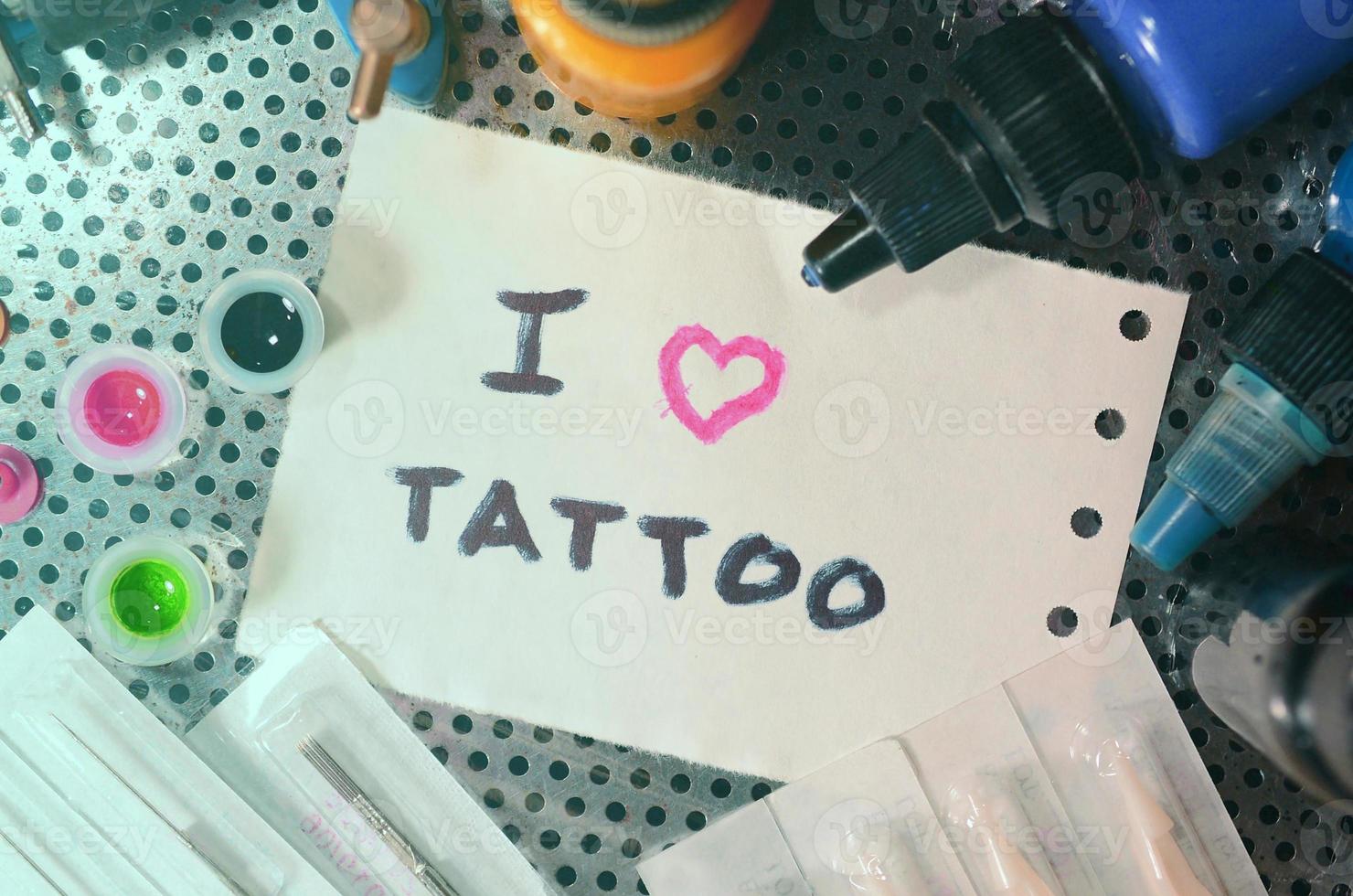 I love tattoo. The text is written on a small sheet of paper among various equipment for tattooing photo