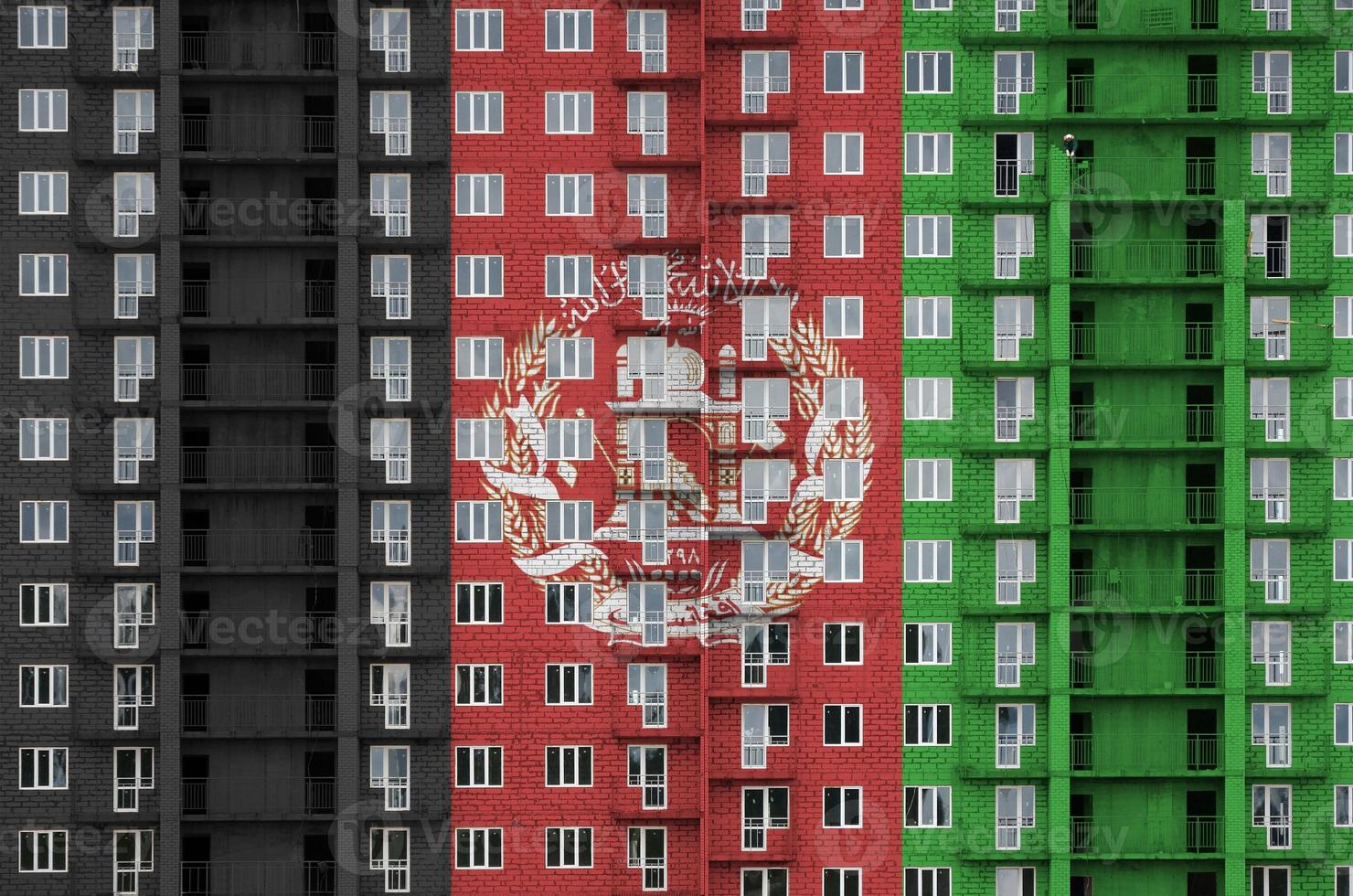 Afghanistan flag depicted in paint colors on multi-storey residental building under construction. Textured banner on brick wall background photo