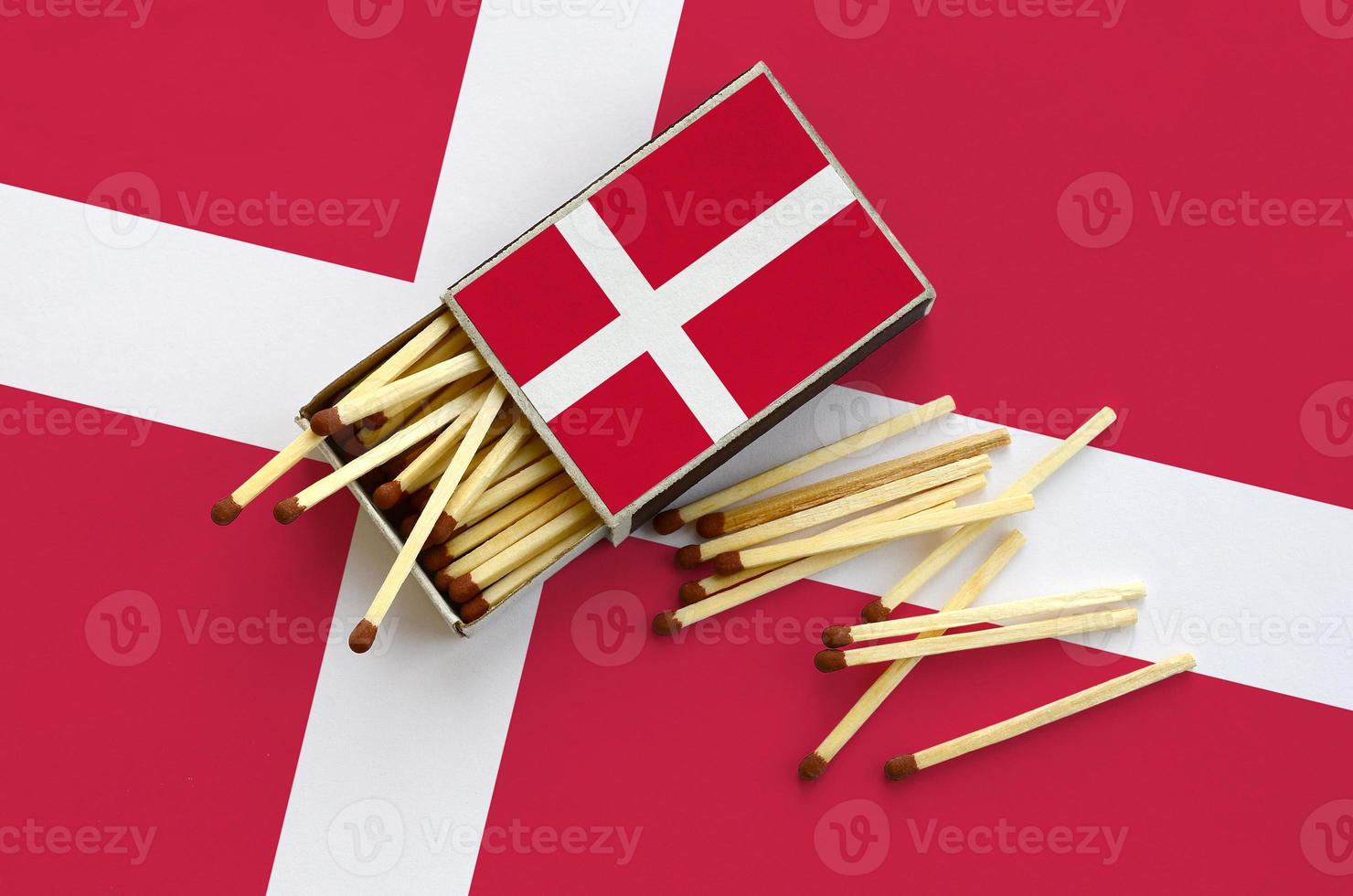 Denmark flag  is shown on an open matchbox, from which several matches fall and lies on a large flag photo