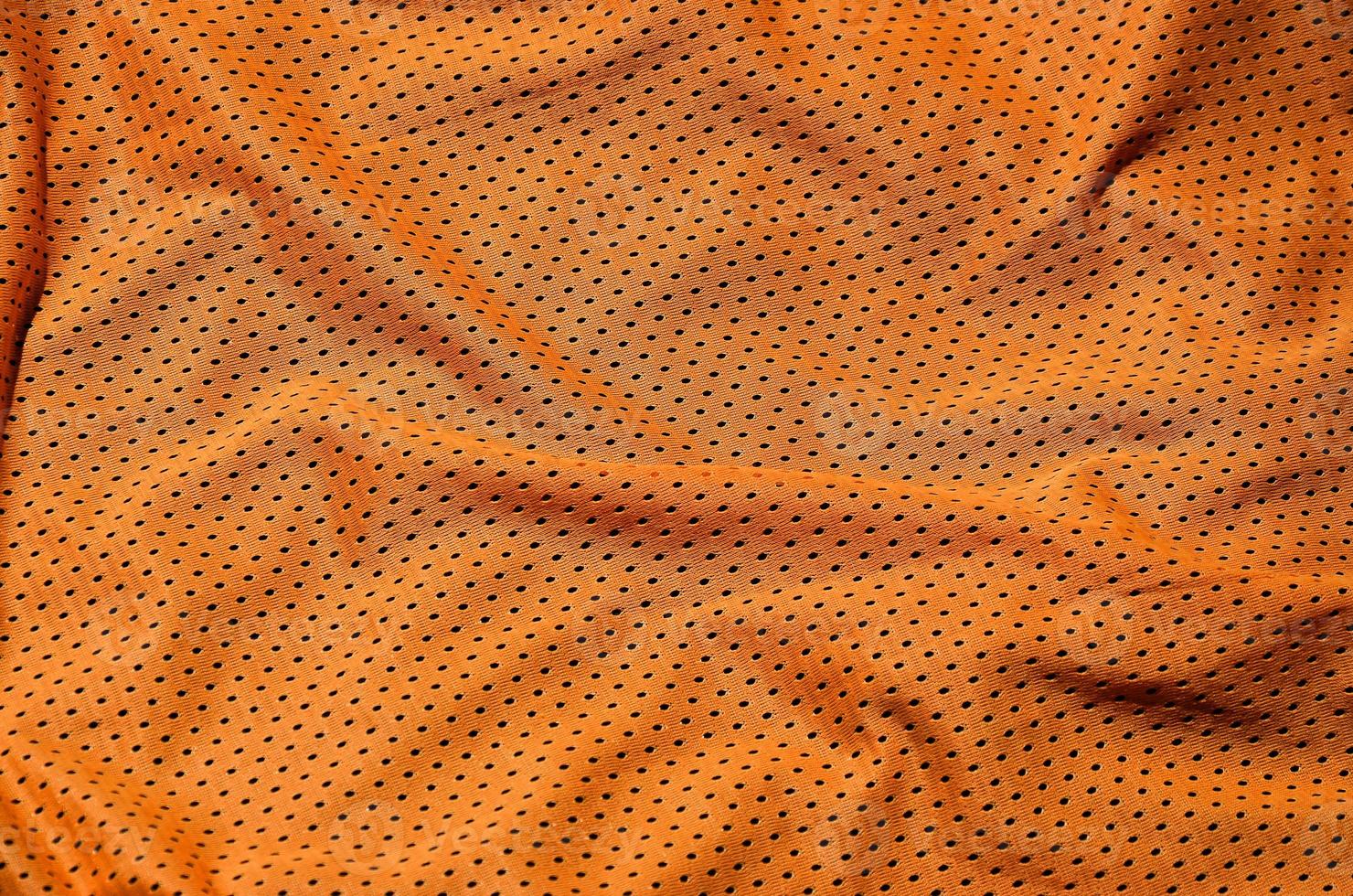 Sport clothing fabric texture background. Top view of orange polyester nylon cloth textile surface. Colored basketball shirt with free space for text photo