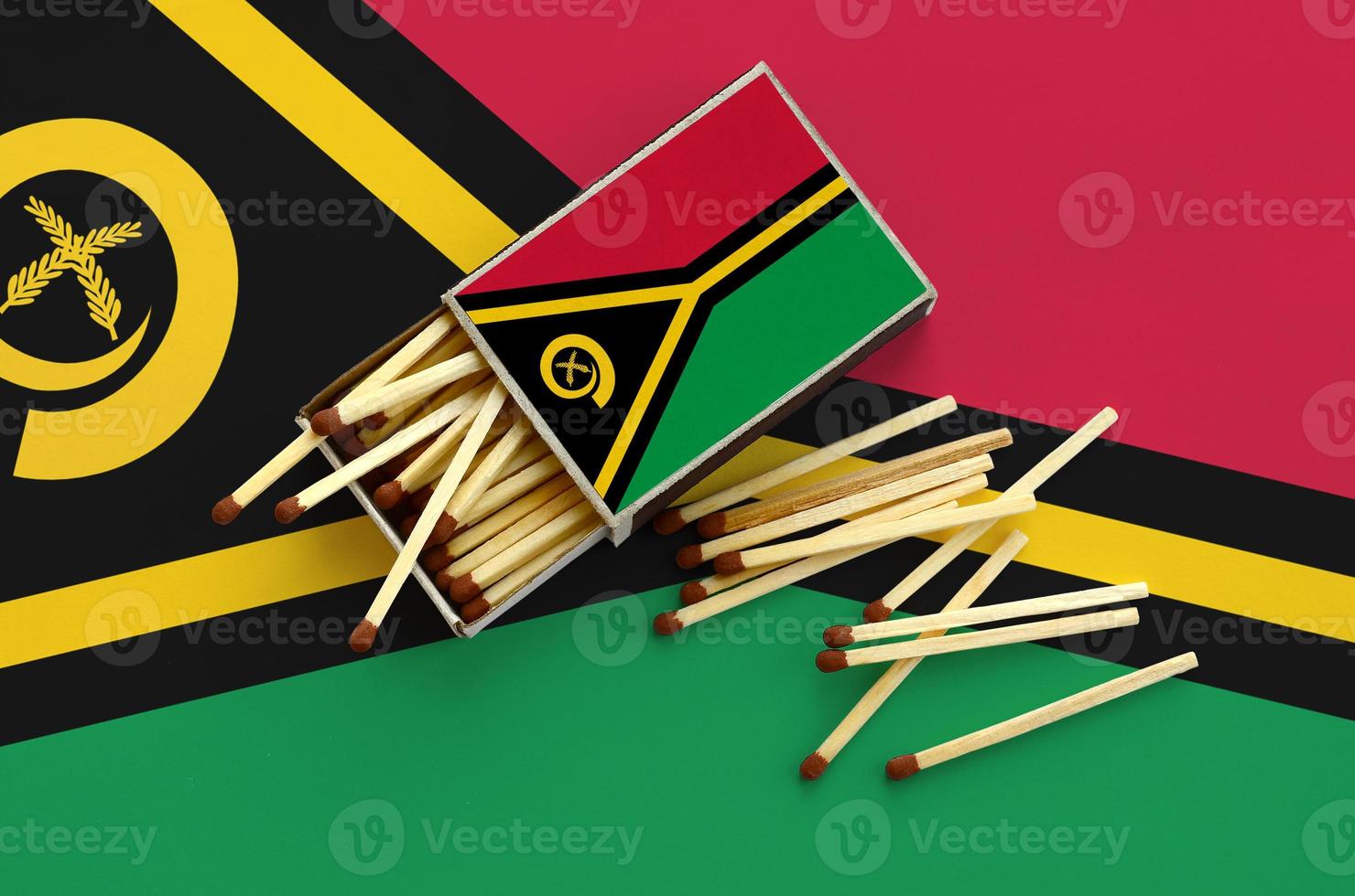 Vanuatu flag  is shown on an open matchbox, from which several matches fall and lies on a large flag photo