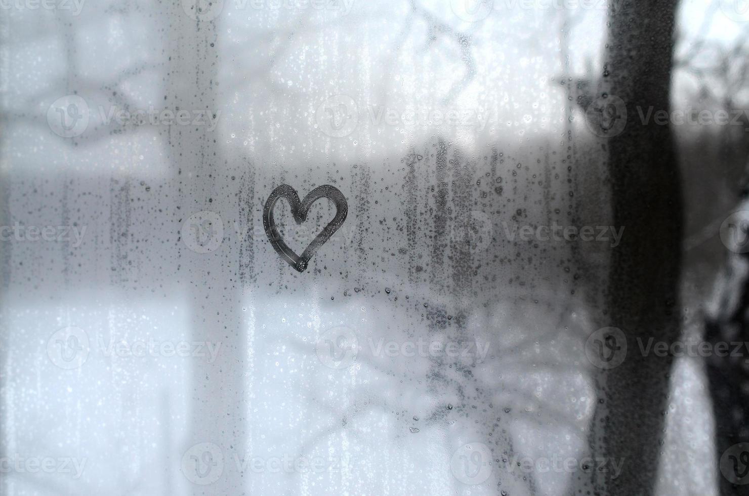 The heart is painted on the misted glass in the winter photo