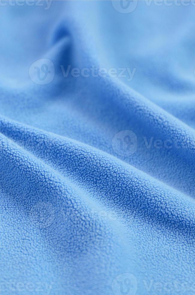 The blanket of furry blue fleece fabric. A background of light blue soft plush fleece material with a lot of relief folds photo