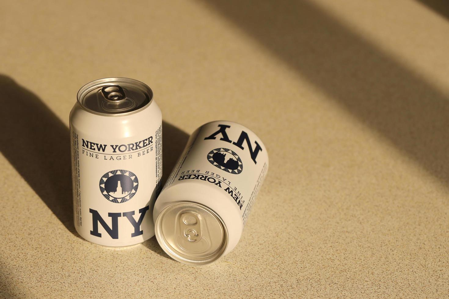TERNOPIL, UKRAINE - JULY 18, 2022 Two cans of New Yorker fine lager beer with original logo and design on brown retro background photo