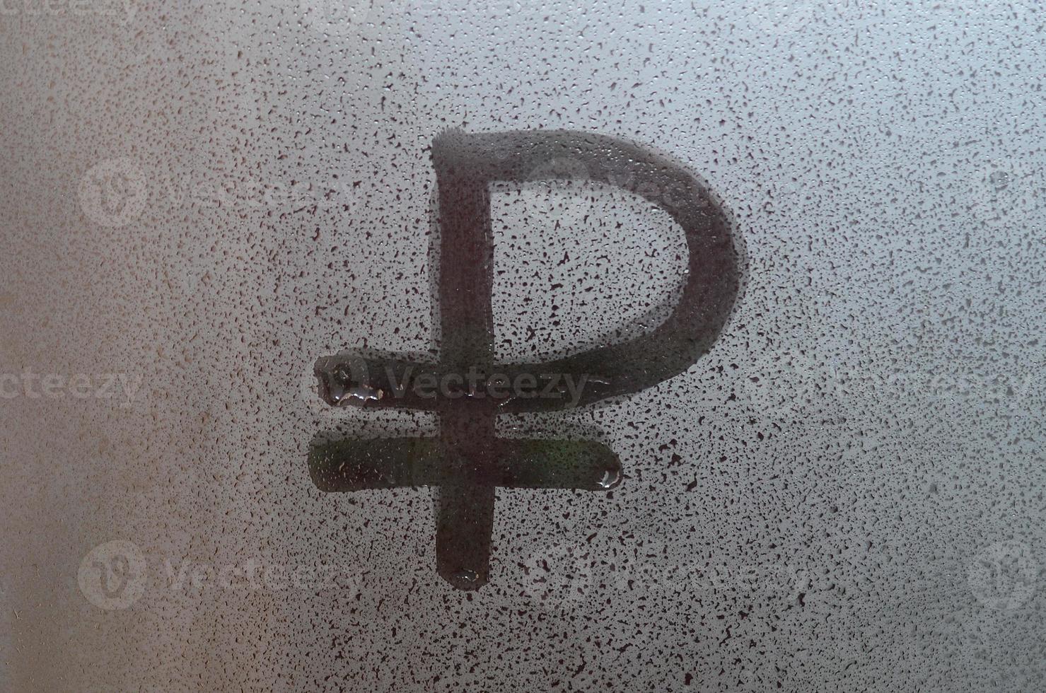 Symbol of the Russian ruble is written with a finger on the surface of the misted glass photo