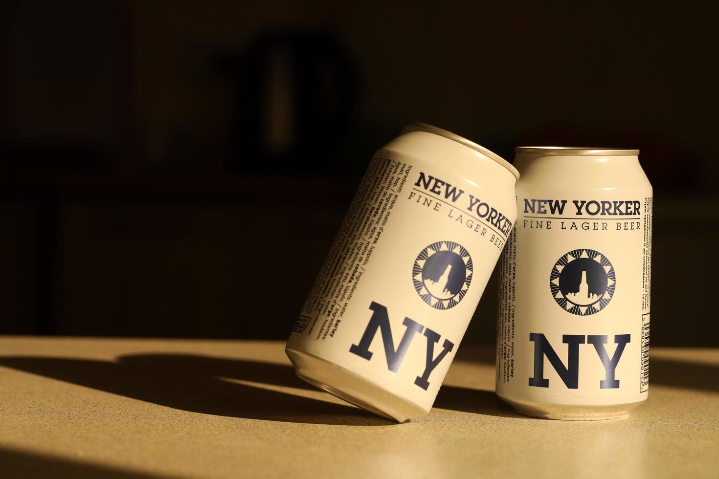 TERNOPIL, UKRAINE - JULY 18, 2022 Two cans of New Yorker fine lager beer with original logo and design on brown retro background photo