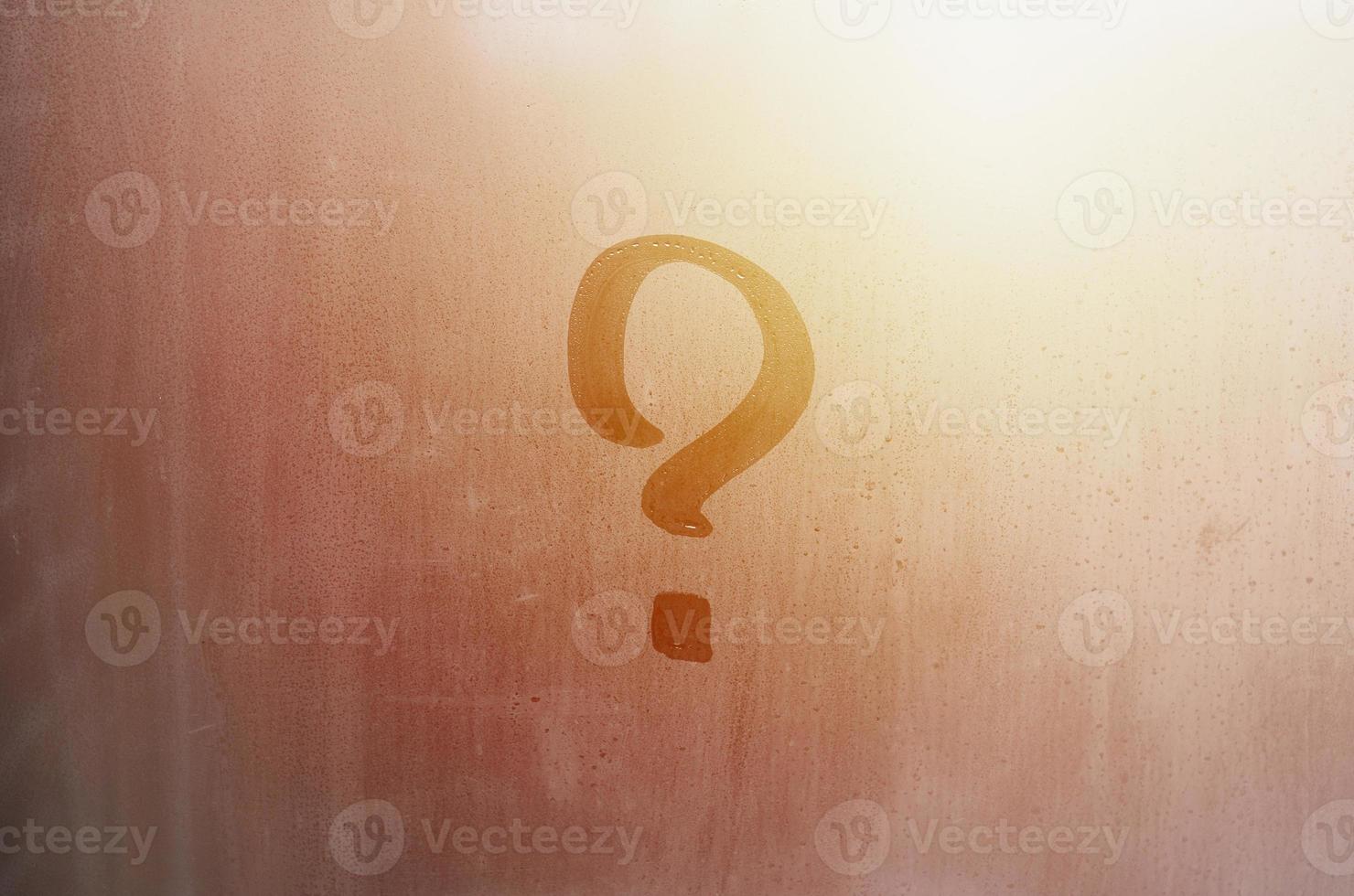 The inscription on glass, question mark concept. Question sign is painted on the surface of misted and wet window photo