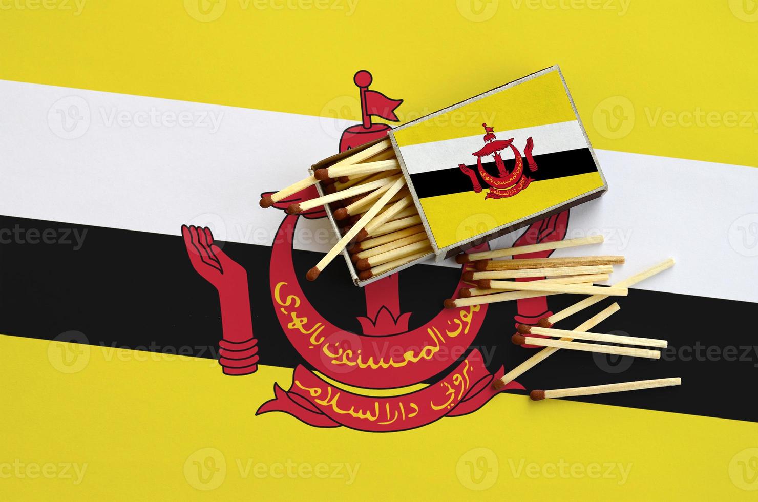 Brunei Darussalam flag  is shown on an open matchbox, from which several matches fall and lies on a large flag photo