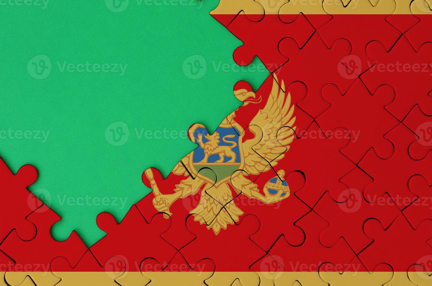 Montenegro flag  is depicted on a completed jigsaw puzzle with free green copy space on the left side photo