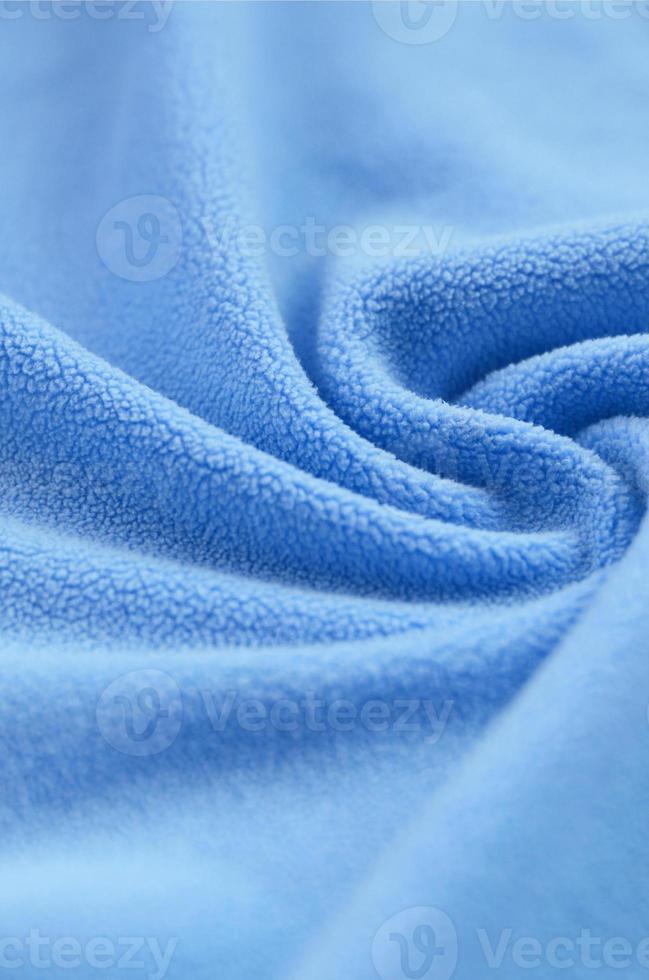 The blanket of furry blue fleece fabric. A background of light blue soft plush fleece material with a lot of relief folds photo