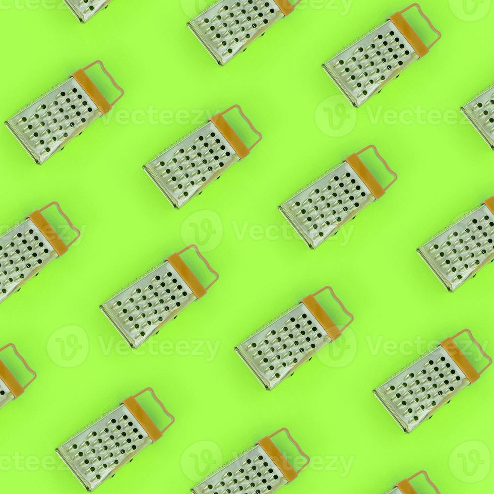 Small stainless steel graters lies on a pastel colored paper. Kitchen accessories. Tools for cooking. Flat lay top view photo