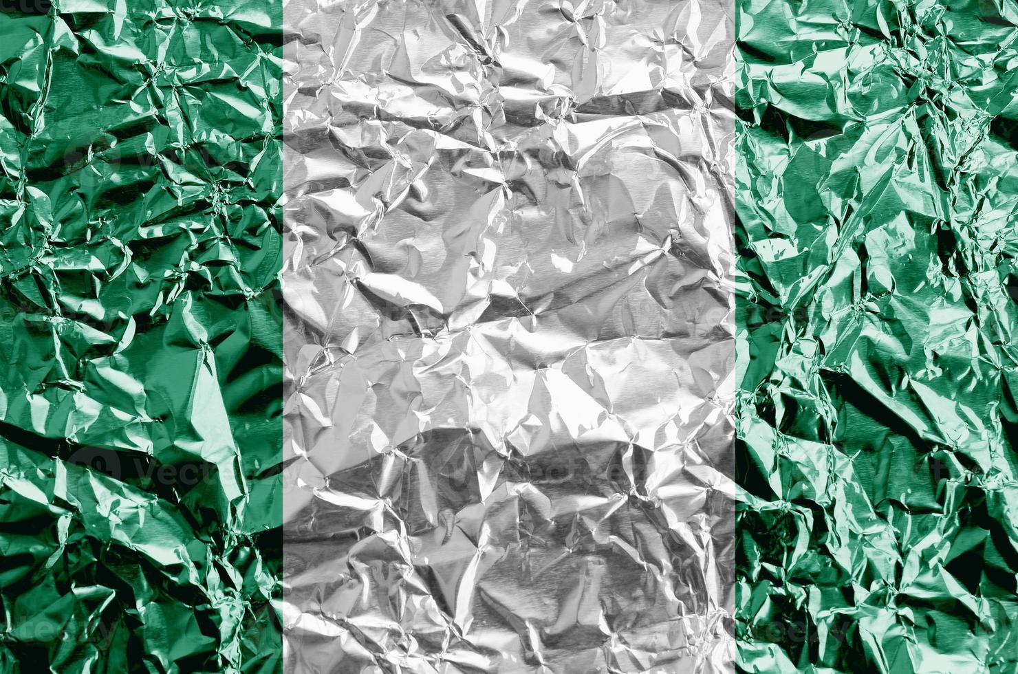 Nigeria flag depicted in paint colors on shiny crumpled aluminium foil closeup. Textured banner on rough background photo