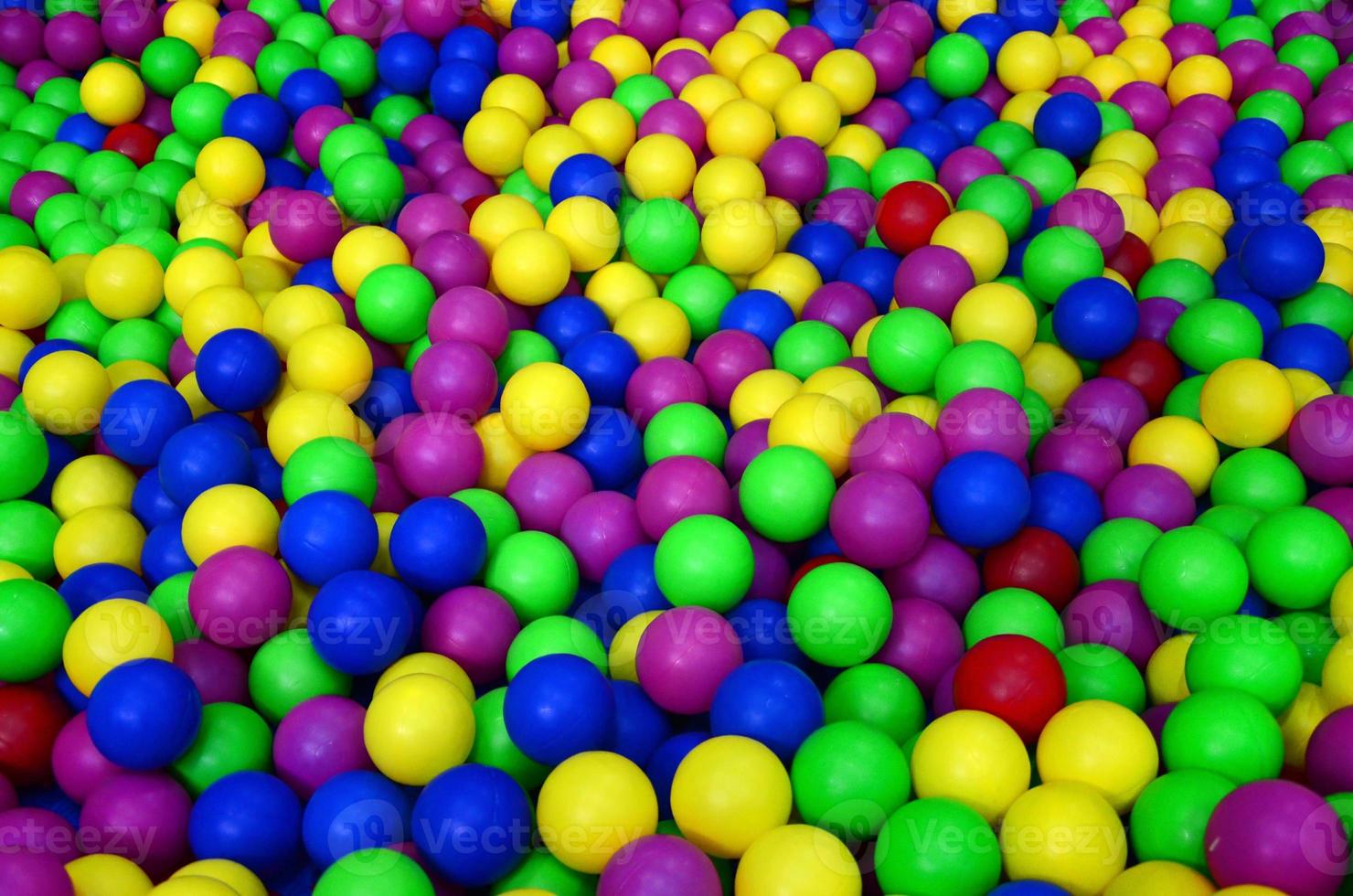 Many colorful plastic balls in a kids' ballpit at a playground. Close up pattern photo
