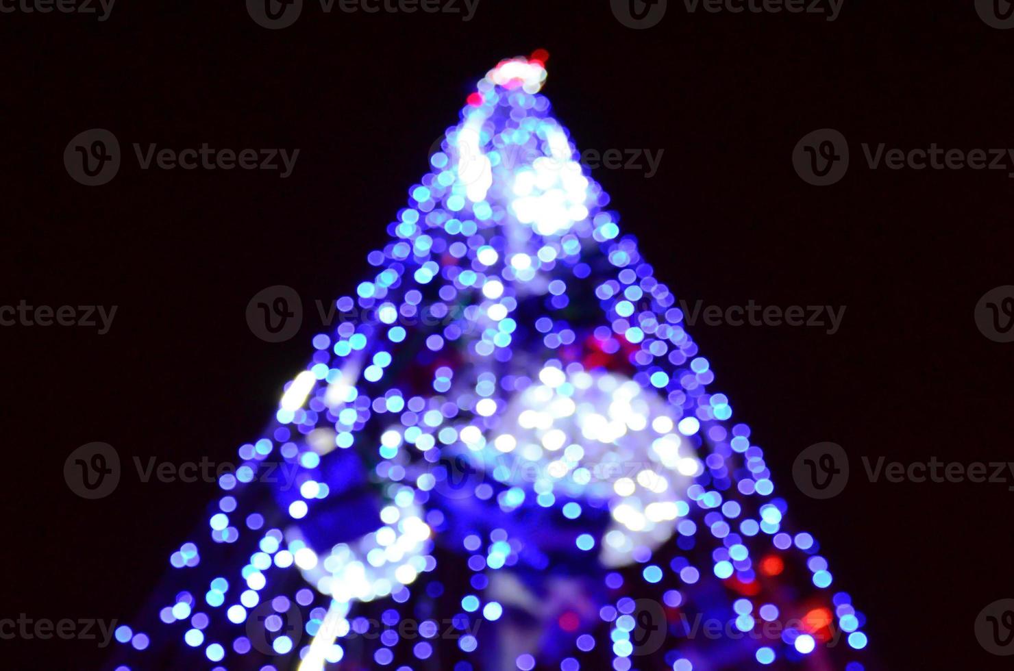 Blurred fragment of the New Year tree. Lots of round lights in blue photo