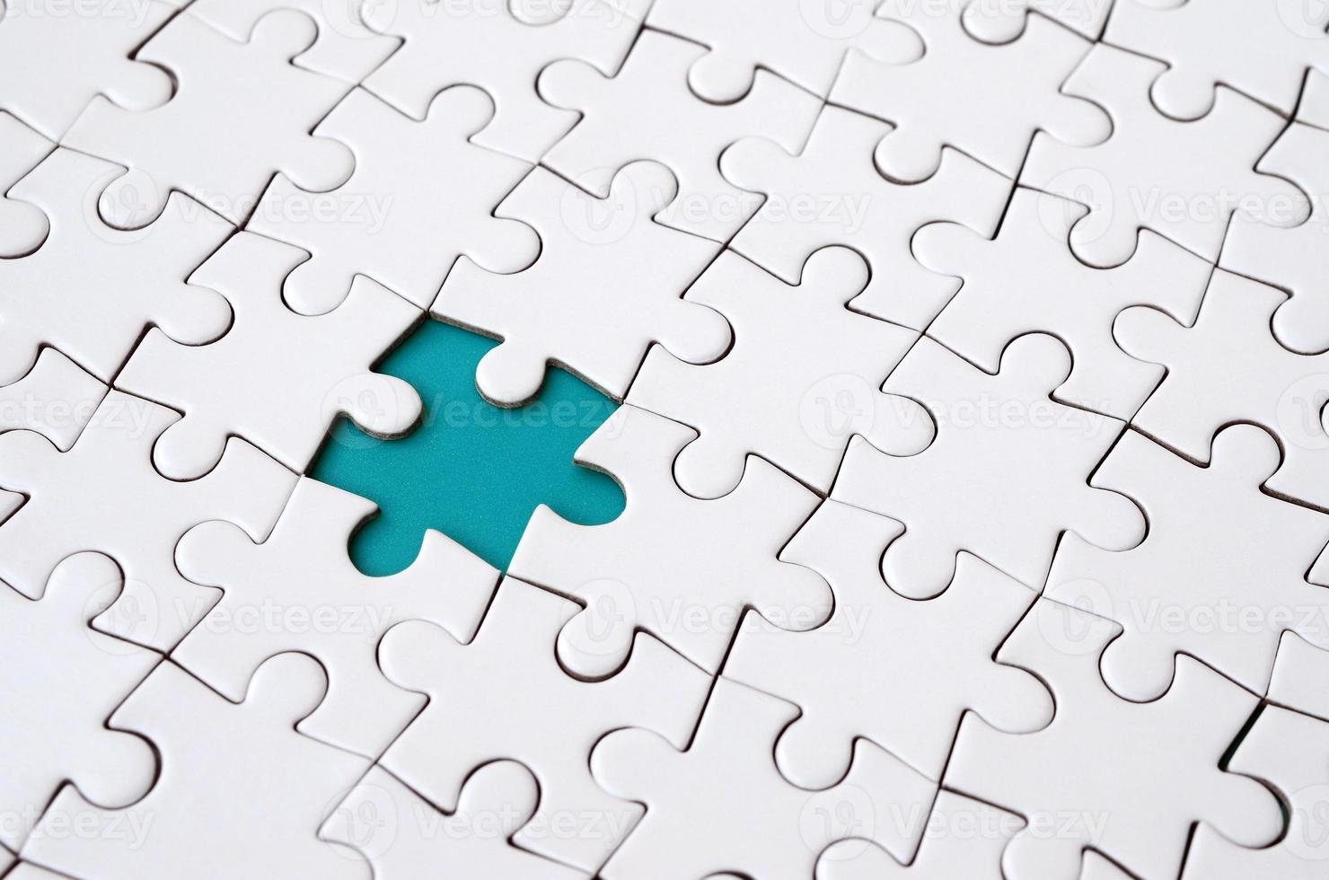 Close-up texture of a white jigsaw puzzle in assembled state with missing elements forming a blue pad for text. Copy space photo