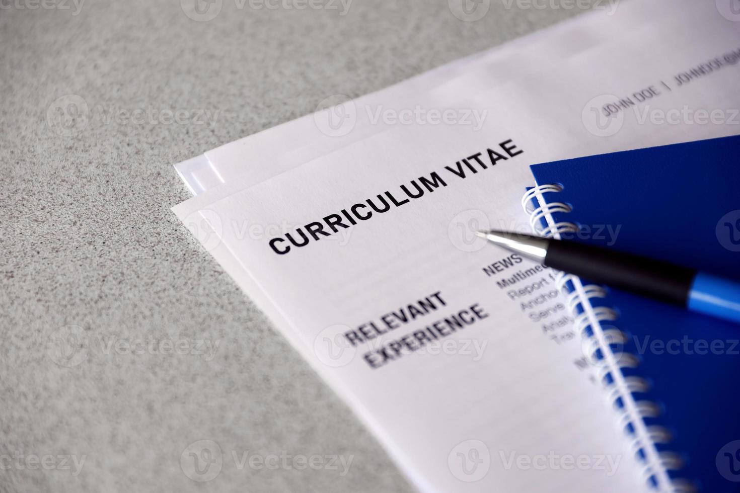 Top view of stack of office documents including resume and cv forms on the desk close to pen and notepad. Job seeking process. Hunting for workplace photo