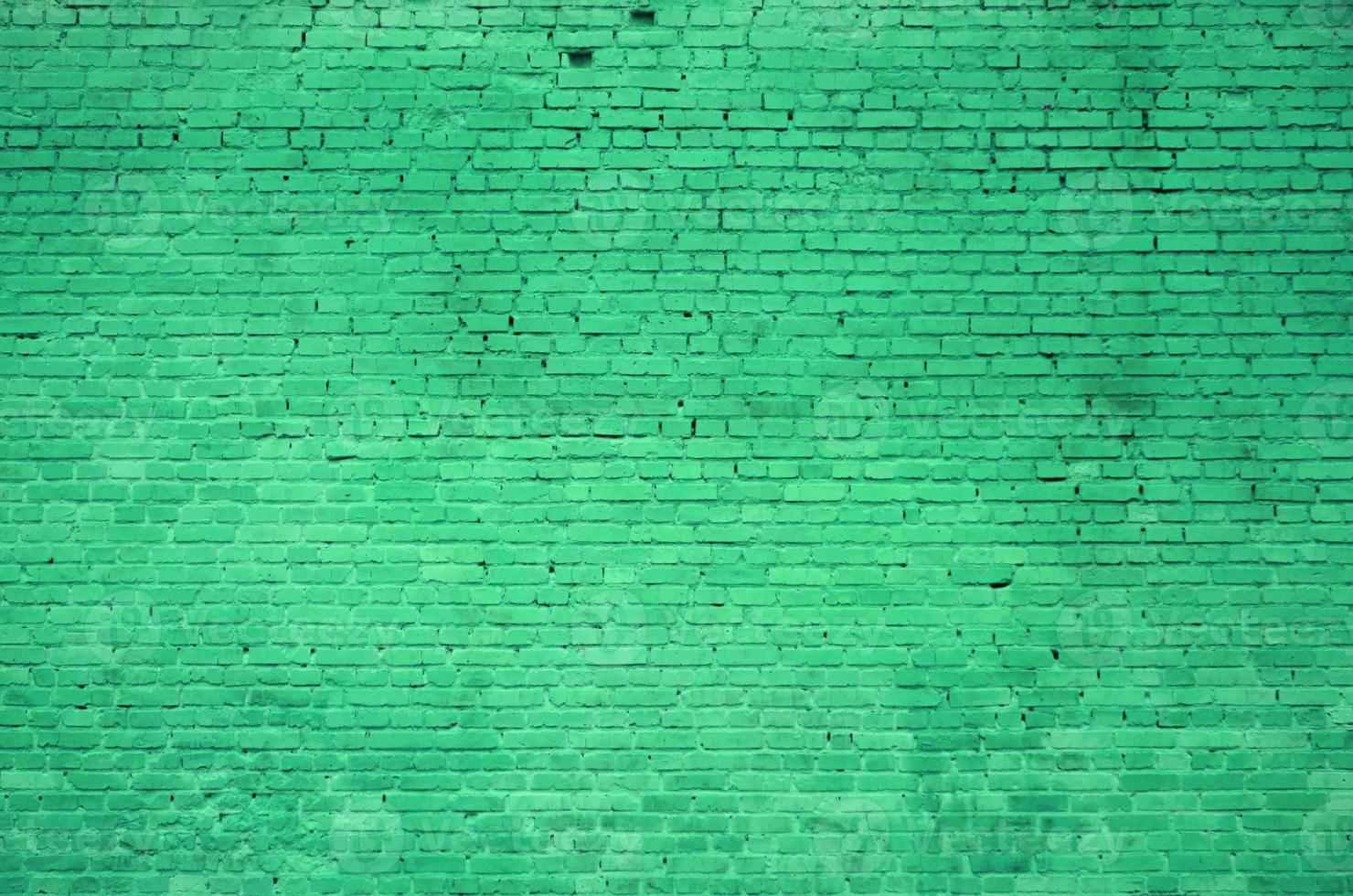 The texture of the brick wall of many rows of bricks painted in green color photo