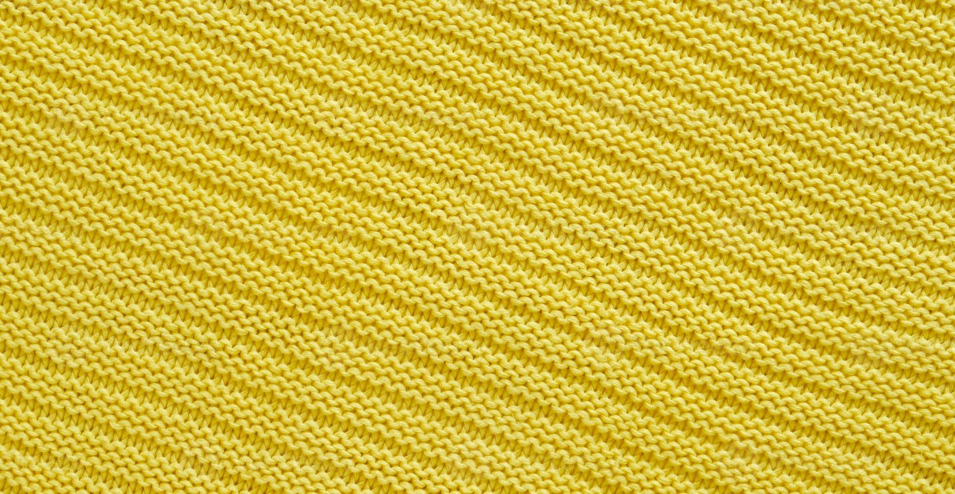 Texture of smooth knitted yellow sweater with pattern. Top view, close-up. Handmade knitting wool or cotton fabric texture. Background of knitting patterns. photo