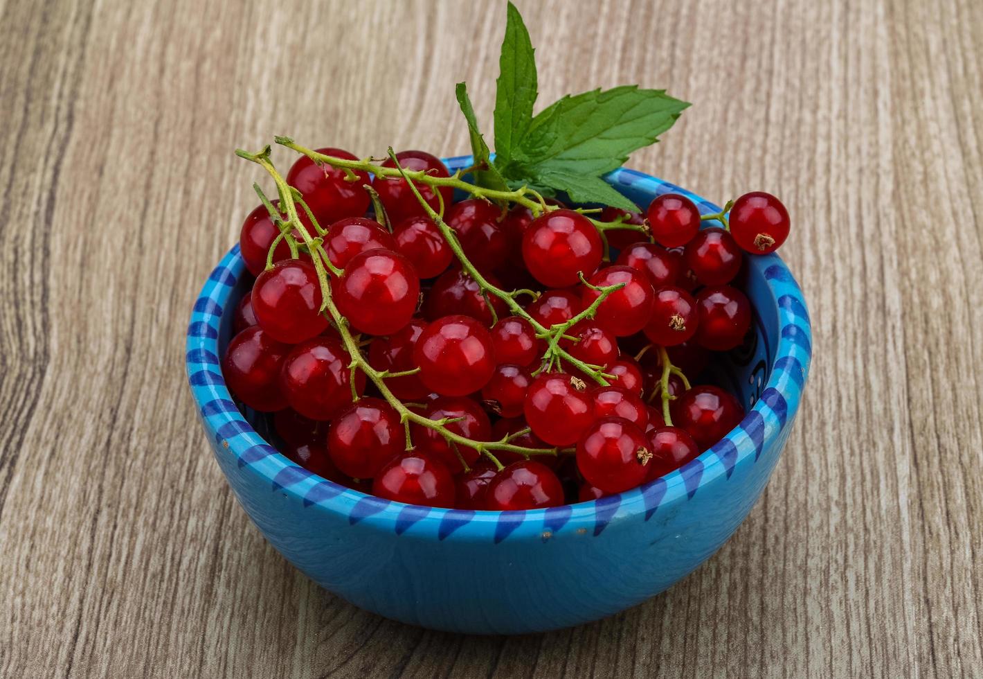 Red currants in a bowl on wooden background photo