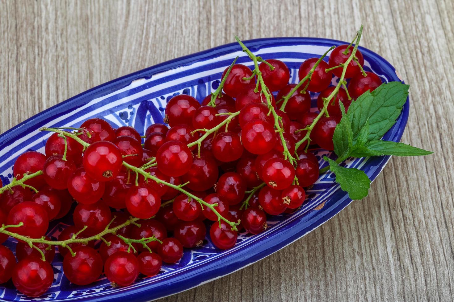 Red currants in a bowl on wooden background photo