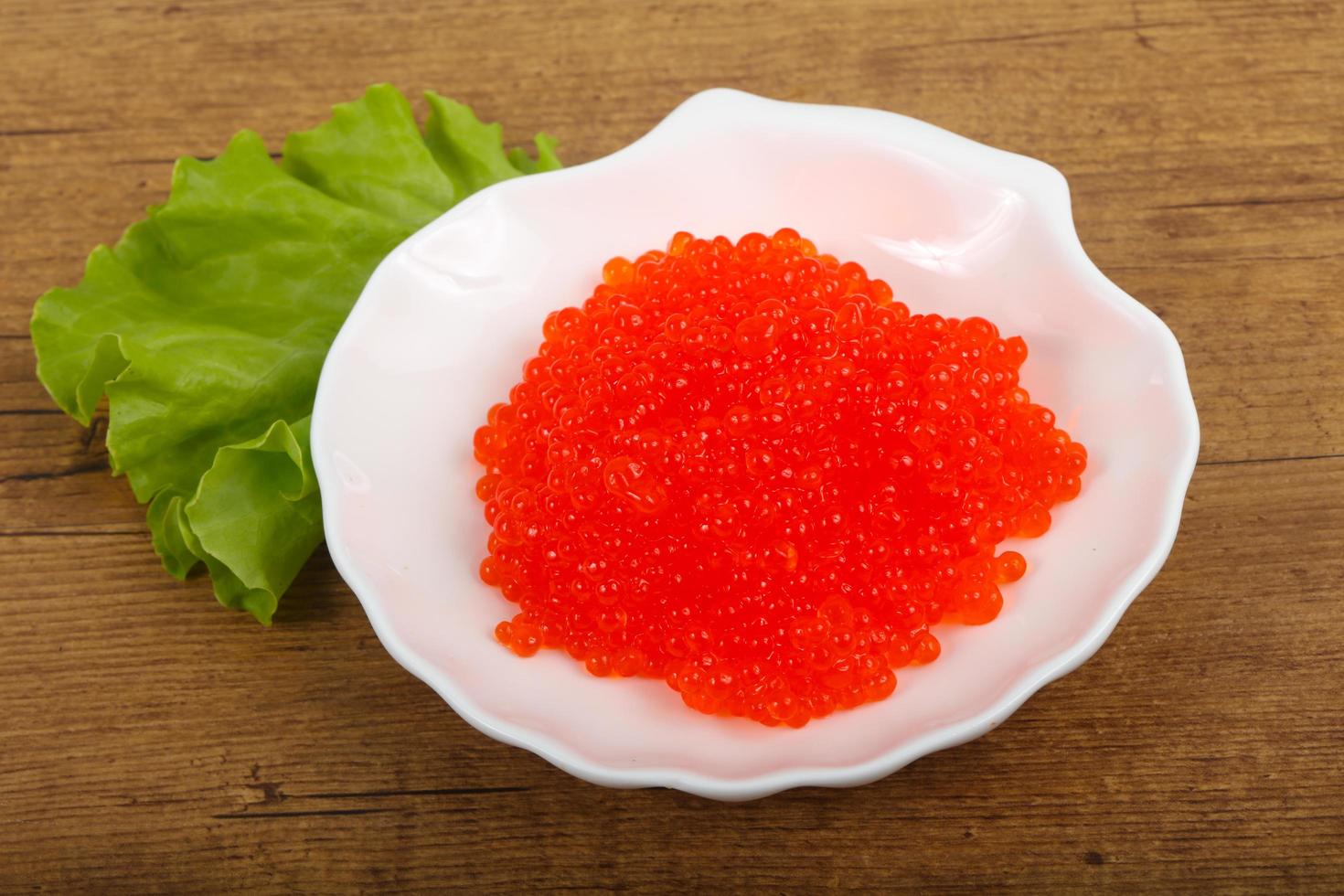 Red caviar on the plate and wooden background photo