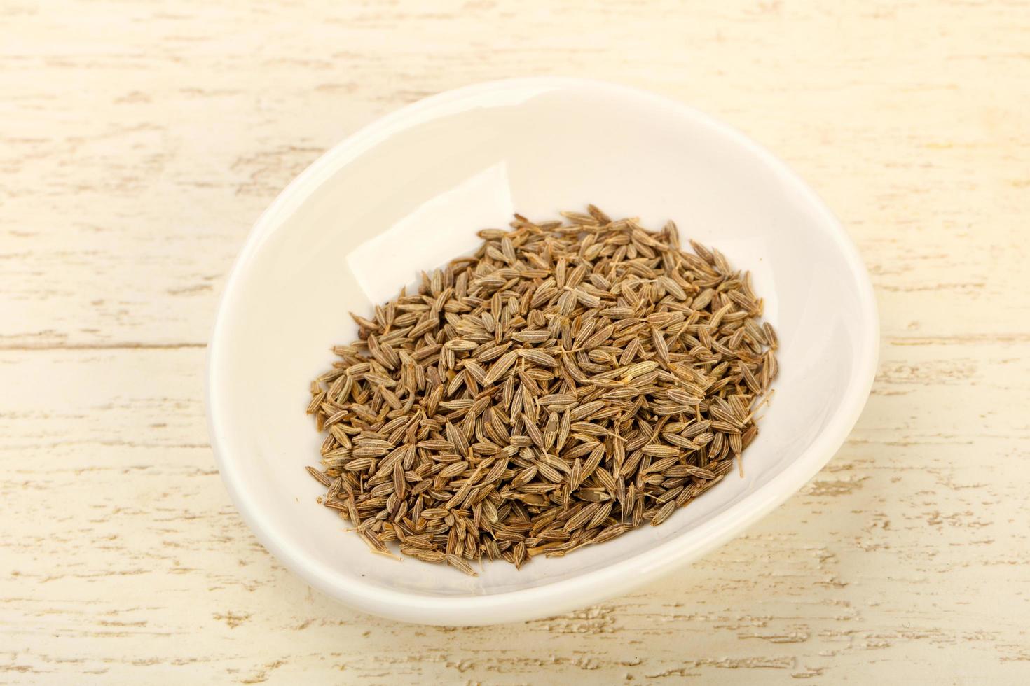 Cumin seeds in a bowl on wooden background photo