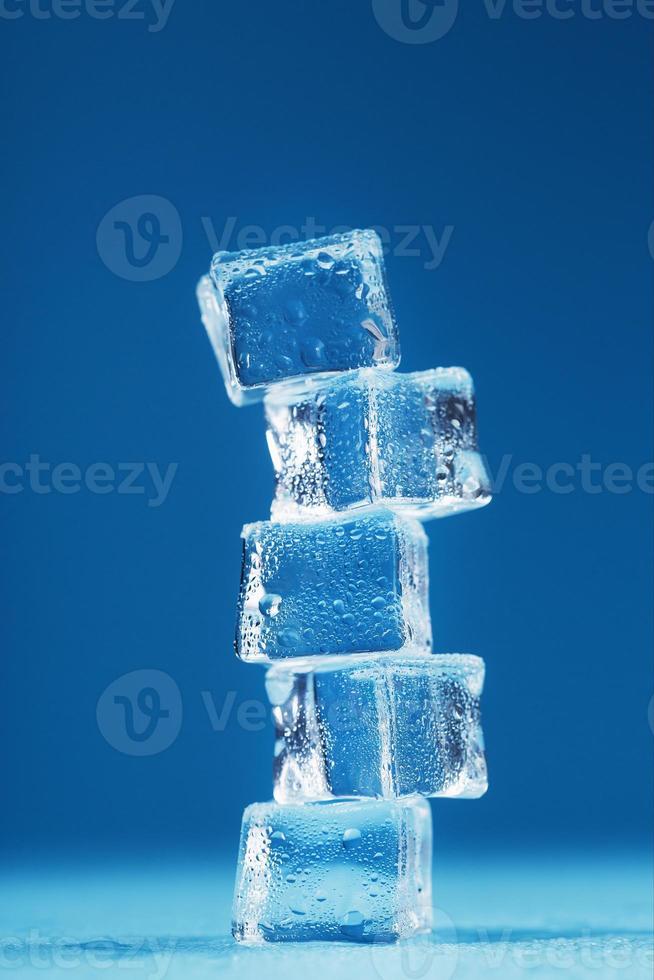 cubos de torre de hielo derritiéndose sobre un fondo azul. foto