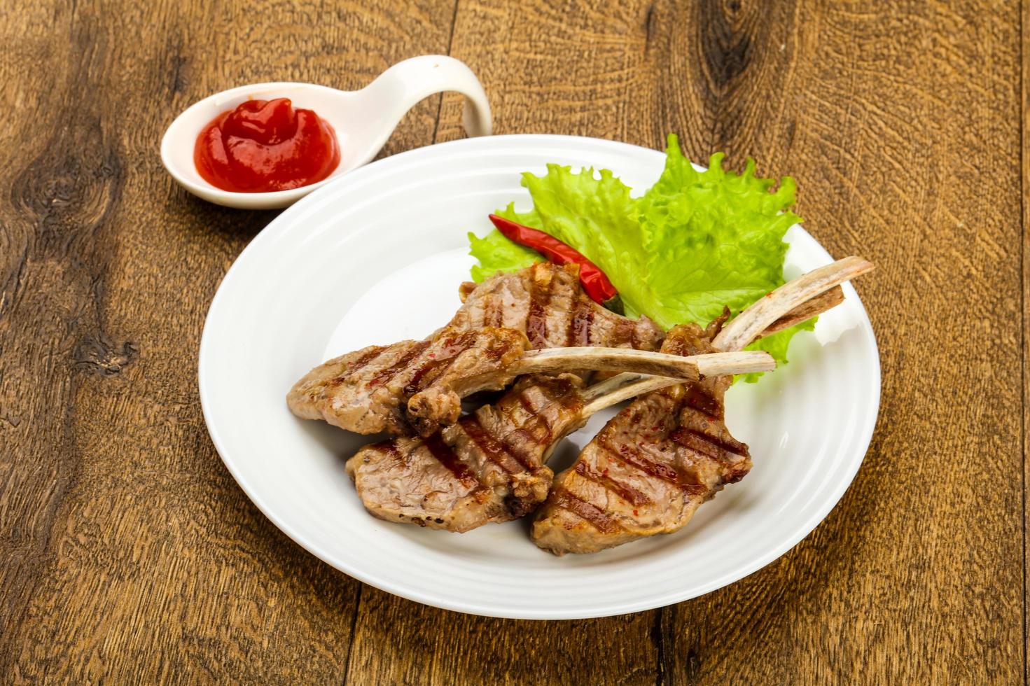 Grilled lamb on the plate and wooden background photo